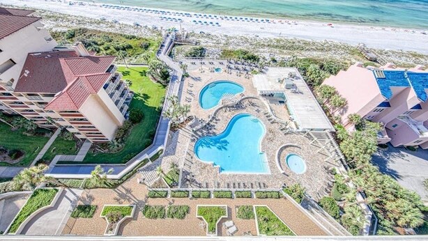 Un complex turístic amb zona de piscina, accés a la platja i diversos edificis.