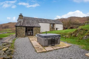 A stone house with a hot tub in the yard.