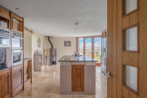 A modern kitchen with a central island, built-in appliances, and a large window overlooking a scenic landscape.