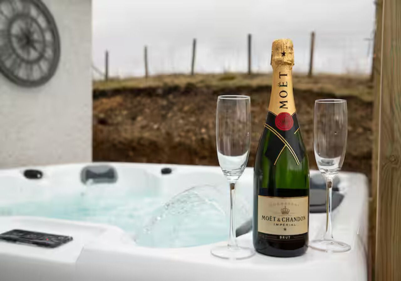 A bottle of Moët & Chandon Imperial Brut champagne, two empty glasses, and a hot tub with a control panel.