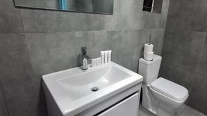 A bathroom with a white sink, toilet, and storage cabinet. - Neema Lodge (Boksburg)