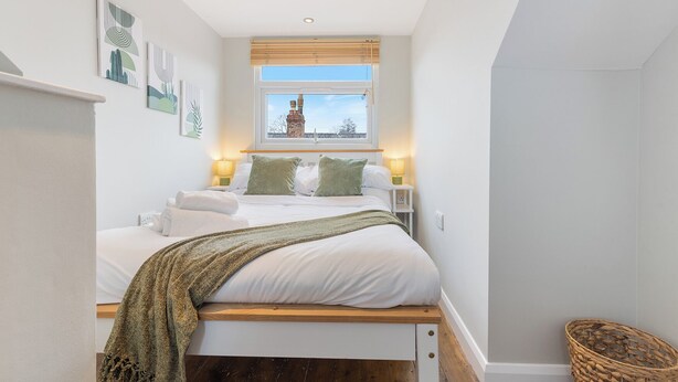 Une chambre à coucher avec un lit, des lampes de chevet, une fenêtre donnant sur un beau paysage et des œuvres d’art accrochées au mur.