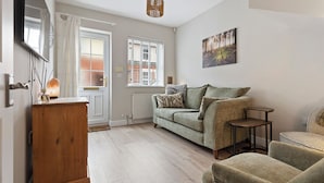 Un salon comprenant un canapé, une petite table, une chaise, un meuble en bois, un radiateur et un tableau accroché au mur.