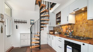 Eine Küche mit weißen Schränken, einer Holztreppe und einer gefliesten Spritzschutzwand.