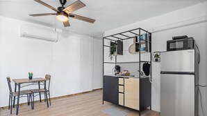 Une cuisine compacte équipée d’un four à micro-ondes encastré, d’un réfrigérateur et d’un ventilateur de plafond.