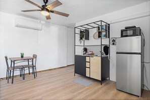 Une cuisine compacte équipée d’un four à micro-ondes encastré, d’un réfrigérateur et d’un ventilateur de plafond.