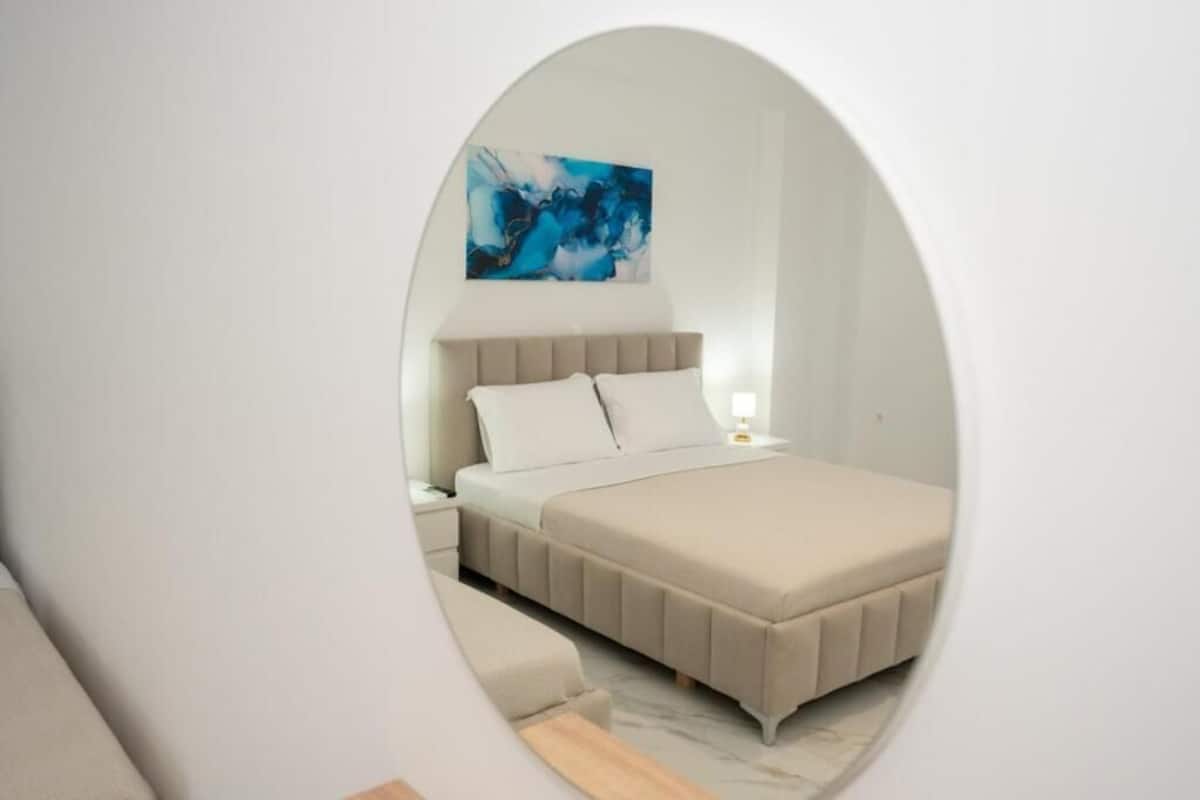 A bedroom with a bed, a nightstand, a wall-mounted abstract painting, and a circular architectural feature.