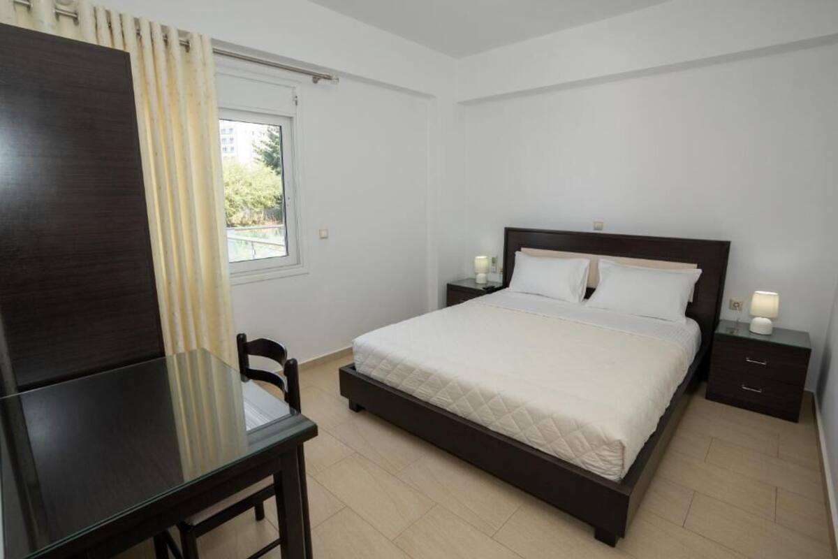 A bedroom with a bed, bedside tables, a desk, and a chair.