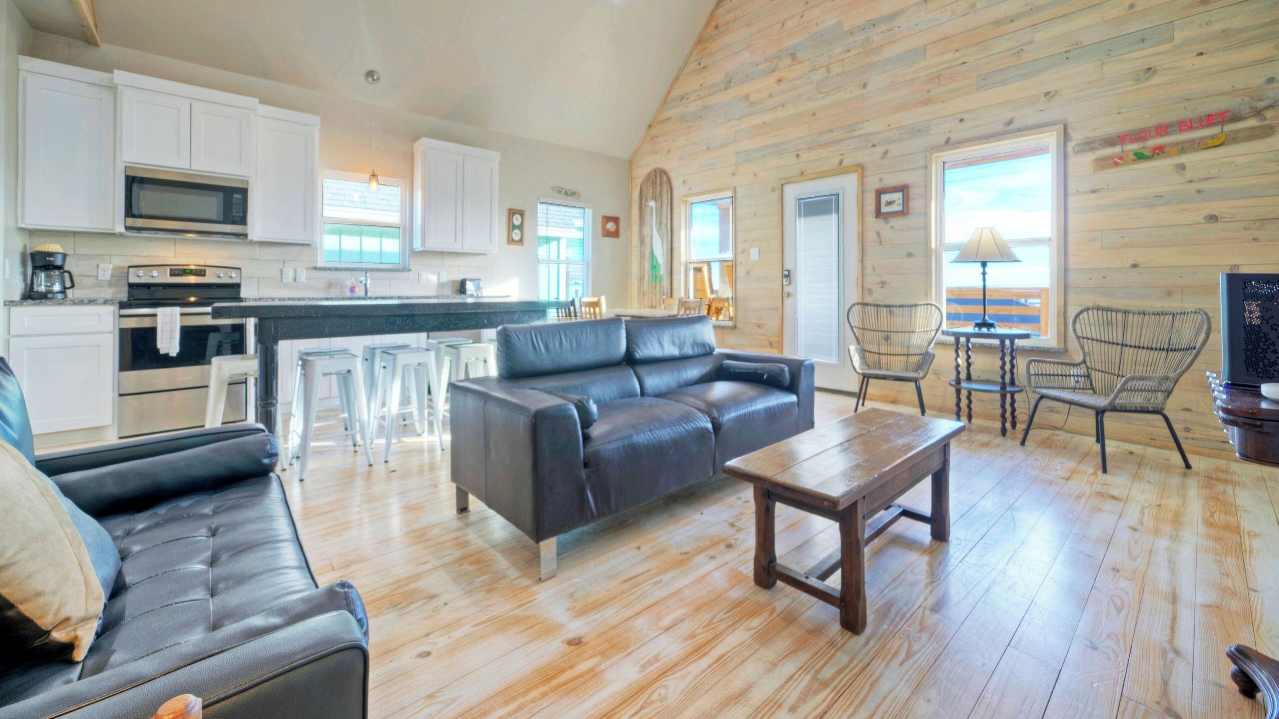 A spacious living area with a sofa, coffee table, and chairs, a kitchen with modern appliances, and a wooden interior.