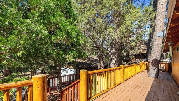 Une terrasse en bois avec une rambarde jaune, entourée d’arbres.
