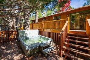 A hot tub in a wooden deck area with a wooden railing and steps leading up to a building. - Big Bear Cozy Cottage (Big Bear Lake)