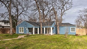 Ein eingeschossiges Haus mit blauer Fassade, einer Veranda und einer sichtbaren Garage.