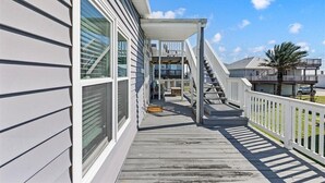 Eine Holzterrasse mit einer überdachten Treppe, die zu einem Balkon im zweiten Obergeschoss führt.