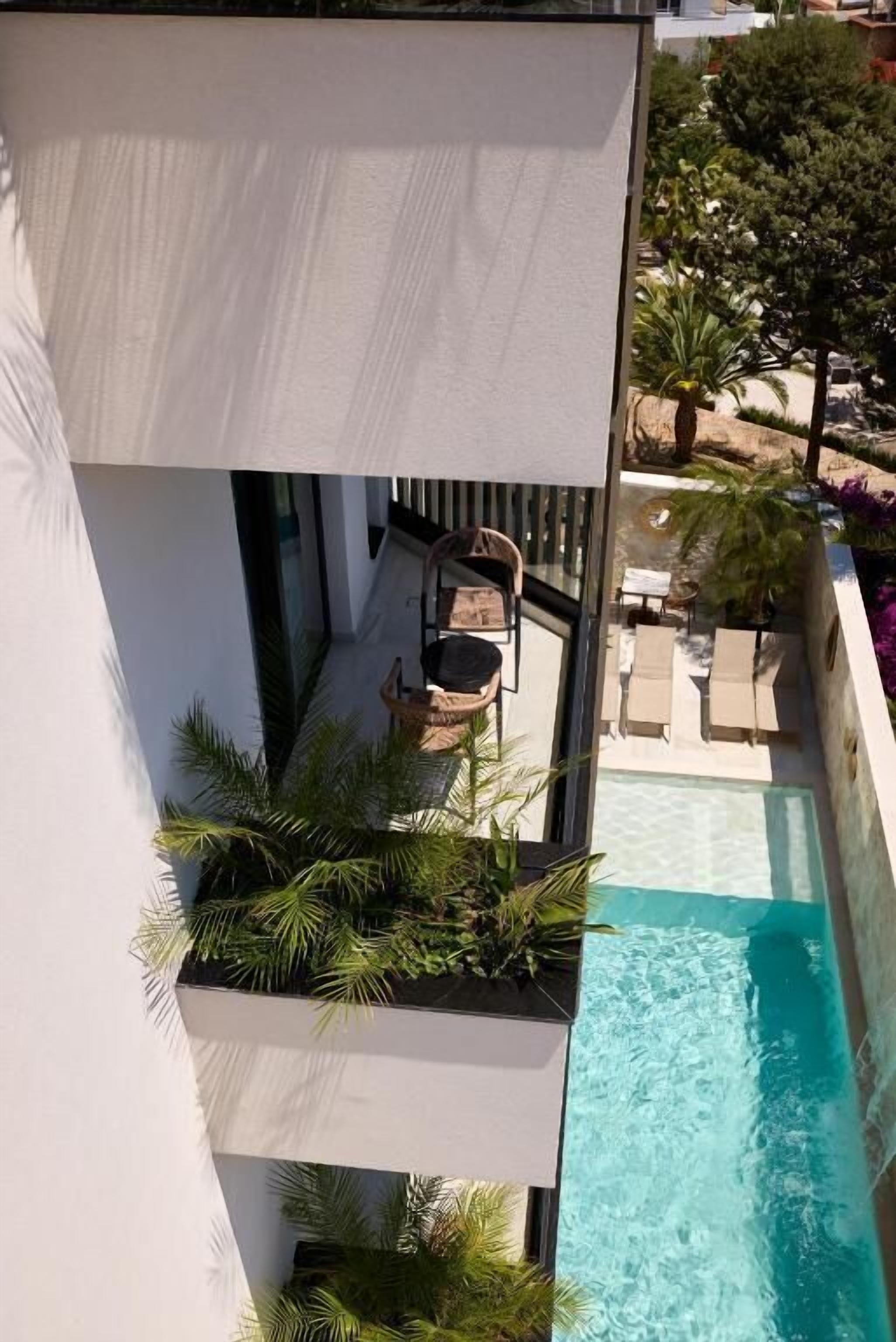 A rooftop pool with a view of the surrounding area, including a seating area with chairs and a table.