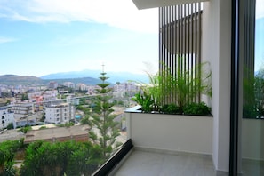 Un balcón con vista a un paisaje urbano, que incluye edificios y montañas.
