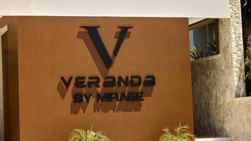 A sign with the text 'VERANDA BY MIRAGE' on a brown wall.