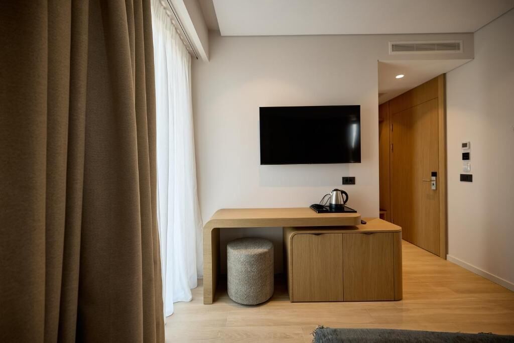 A modern room with a wooden desk, a television mounted on the wall, and a door in the background.