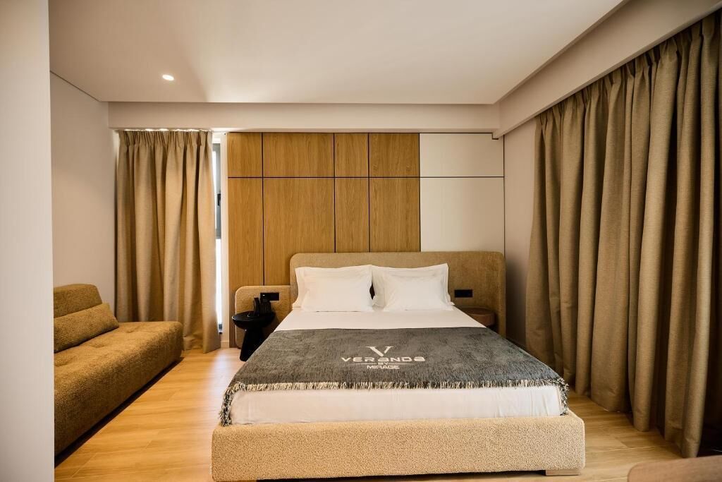 Et moderne hotelværelse med en stor seng, en sofa og en væg beklædt med træpaneler.