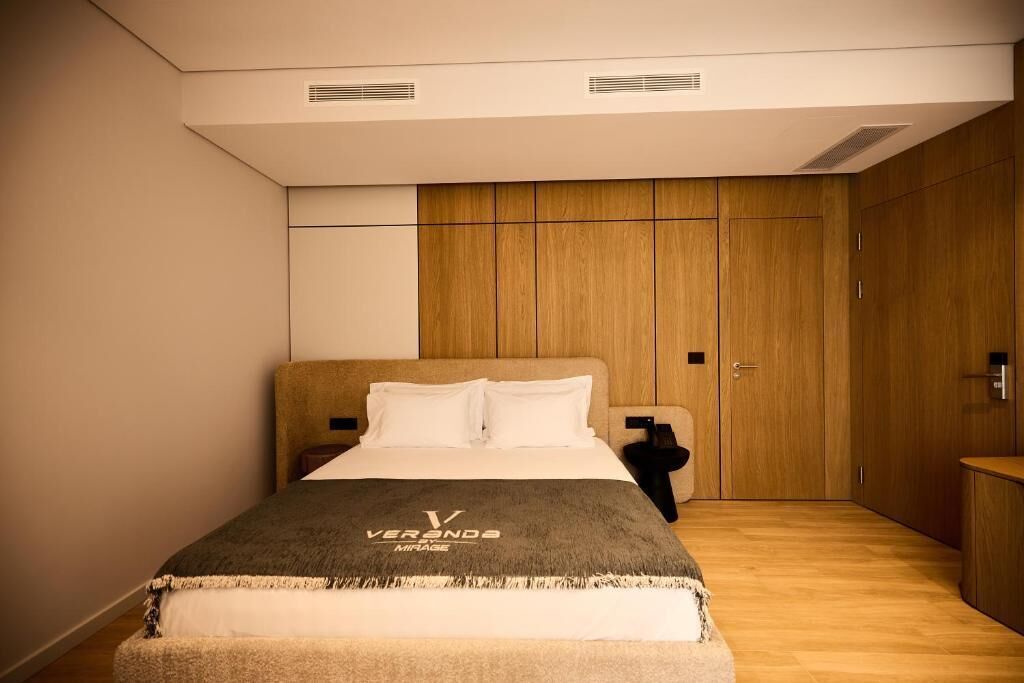 Un dormitorio moderno con cama, armario de madera y mesita de noche.