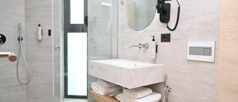A modern bathroom with a glass shower enclosure, a white sink, and a towel rack.