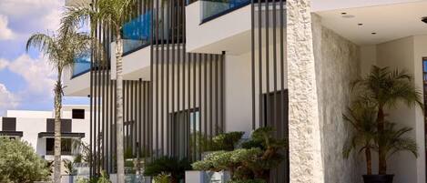 A modern building with vertical lines, balconies, and potted plants.