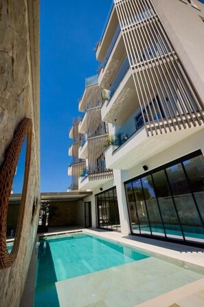 Un edificio moderno con piscina, balcones y ventanas amplias.