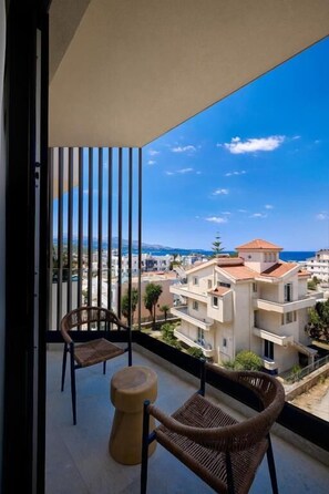Un balcón con muebles de mimbre, vista a edificios y cielo despejado.