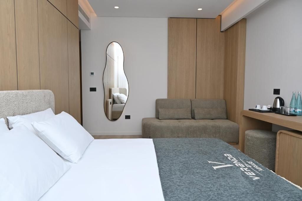 Una camera d'albergo moderna con un letto, un divano, una scrivania e uno specchio.