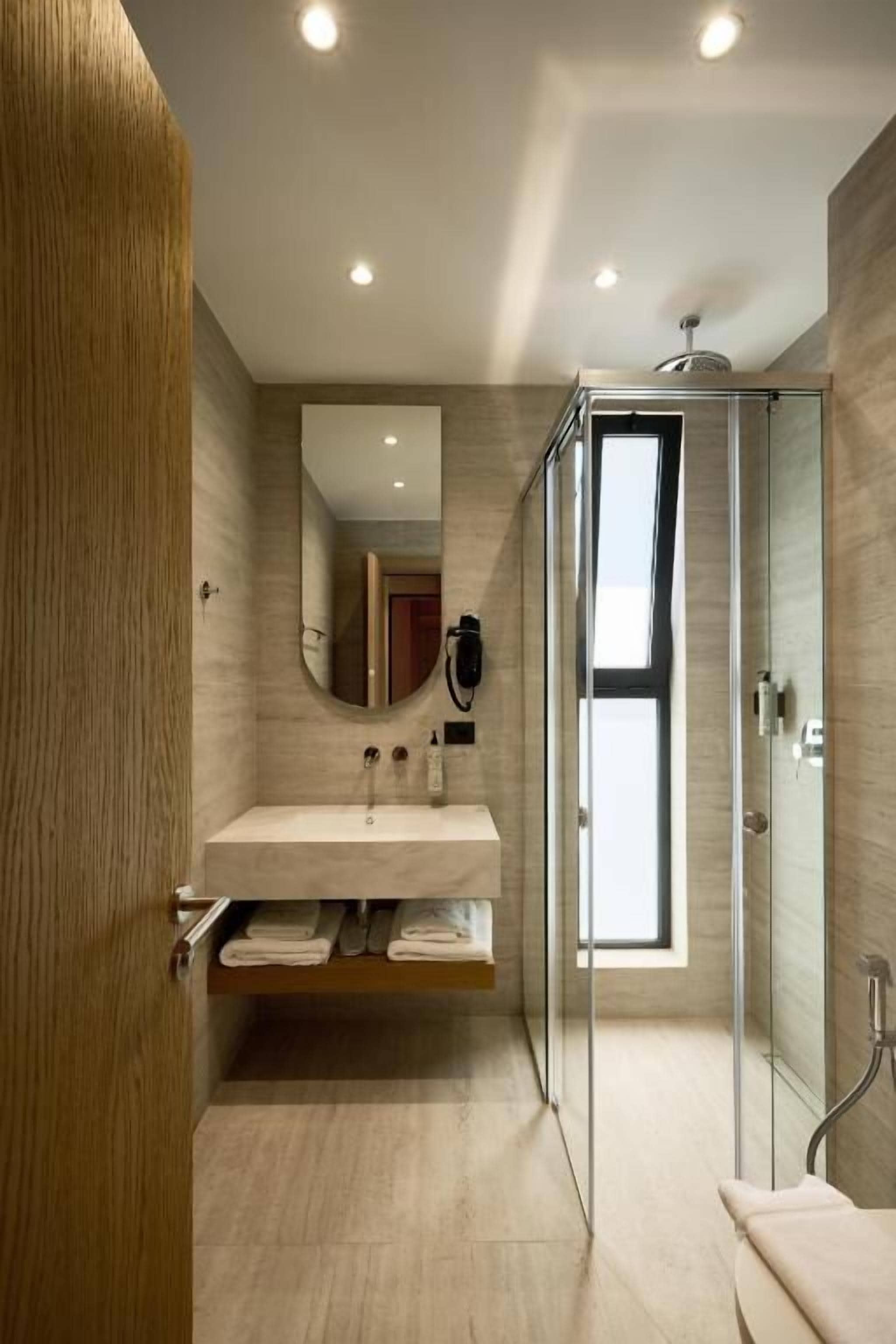 A modern bathroom with a glass shower enclosure, a vanity with a mirror, and a towel rack.