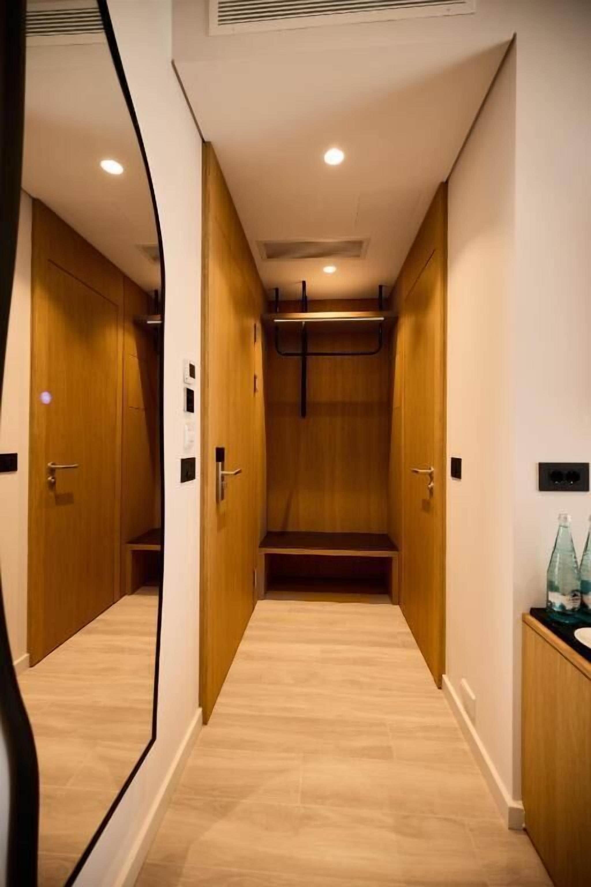 A narrow hallway with wooden doors and a bench.