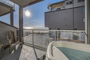 A balcony with a view of the ocean, a chair, and a bathtub.