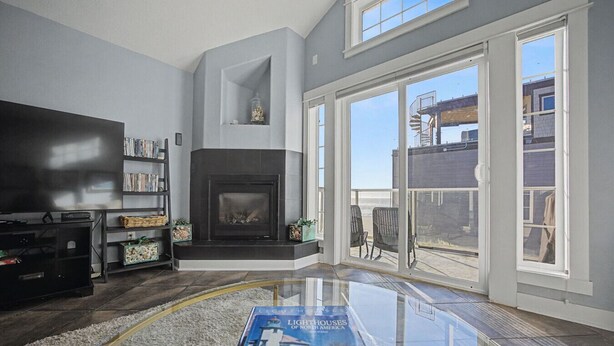 A living room with a fireplace, a bookshelf, a flat-screen TV, and a glass coffee table with a book.