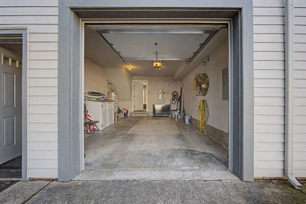 Une entrée de garage avec un sol en béton, une porte et un couloir menant à une pièce.