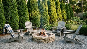 A fire pit with four Adirondack chairs arranged around it, set on gravel with a backdrop of tall evergreen trees. - Azur East,  southampton (Southampton)