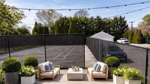 A covered outdoor patio with seating, a basketball court, and a car parked in the background. - Azur East,  southampton (Southampton)