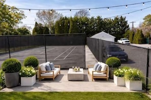 A covered outdoor patio with seating, a basketball court, and a car parked in the background. - Azur East,  southampton (Southampton)