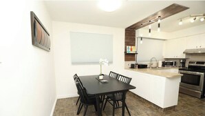Una cucina moderna con mobili bianchi, un'isola centrale ed elettrodomestici in acciaio inossidabile.