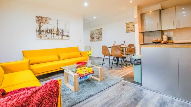 Un salon moderne avec un canapé jaune vif, une table basse en verre et un coin repas comprenant des chaises et une table.