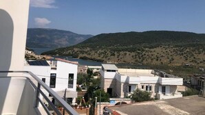 A residential area with modern buildings, a clear view of a lake, and hills in the background. - Hotel Studio Eno Ksamil (Ksamil)