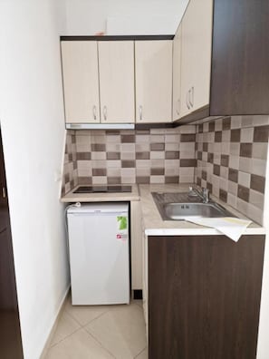 Eine kleine Küche mit Kühlschrank, Spüle und gefliestem Fliesenspiegel.