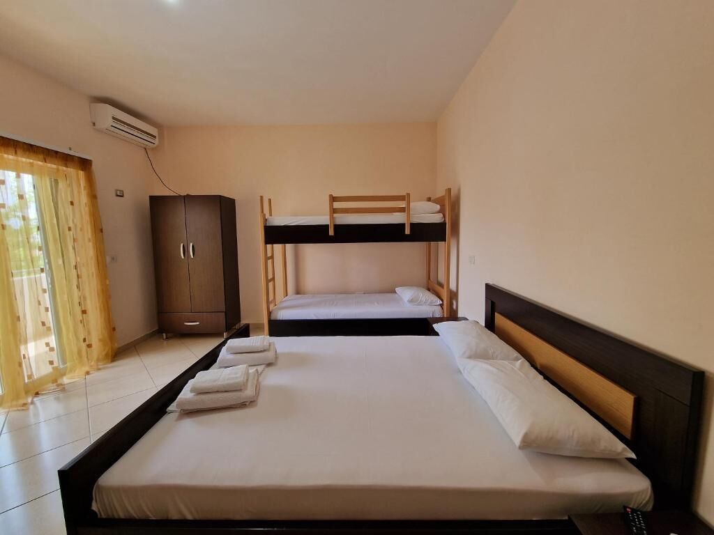 A room with two bunk beds, a wardrobe, and a window with curtains.