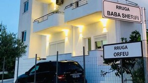 A multi-story building with balconies, a sign indicating 'RRUGA BABA SHERIFI,' and a car parked in front. - Hotel Studio Eno Ksamil (Ksamil)