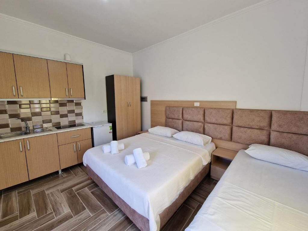 Habitación de hotel con kitchenette, dos camas y un ventanal grande.