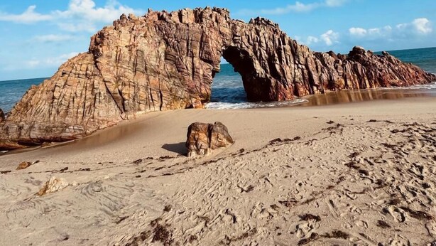 A natural rock arch formation on a beach with clear skies. - Beach House Suítes Jeri (Jijoca de Jericoacoara)