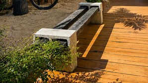 A courtyard with a wooden deck, a bicycle, and potted plants. - Beach House Suítes Jeri (Jijoca de Jericoacoara)