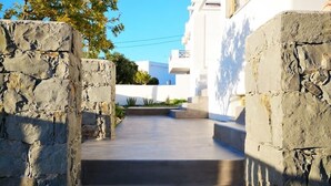 Un chemin de pierres mène à un bâtiment aux murs blancs, sous un ciel d’un bleu limpide.