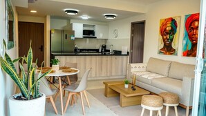 A modern living room with a sofa, coffee table, dining table, chairs, and a potted plant.
