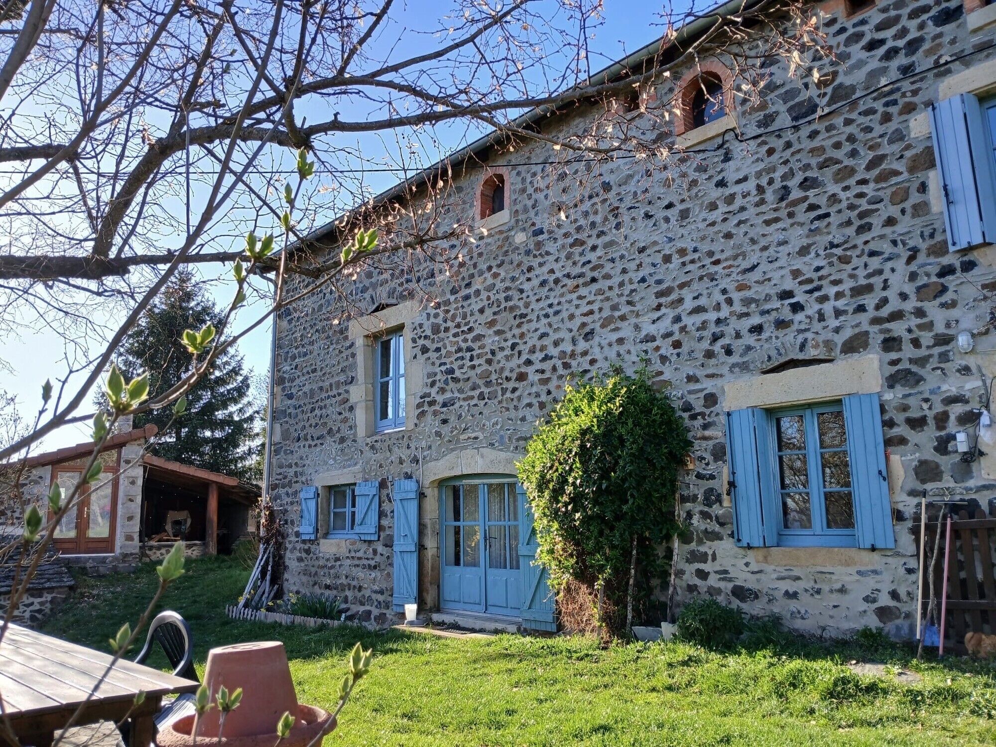 A stone building with blue shutters, a door, and a window.