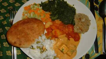 Ein Teller mit Reis, Erbsen, Karotten, Blattgemüse und einem Currygericht.