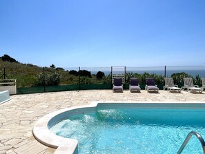 A swimming pool with lounge chairs, a stone deck, and a view of the ocean. - Nativo Big Wave 2BR - Best location to see big waves - Swimming pool (Nazaré)